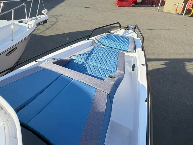 Slide: The Image of 2024 Axopar Cross Cabin boat with blue cushioned seating on deck. - 2