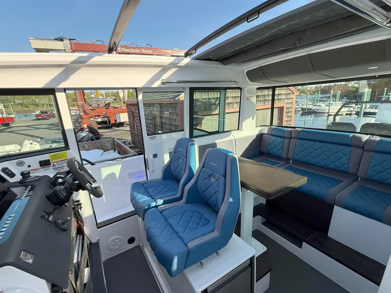 Slide: The Image of 2024 Axopar Cross Cabin interior with blue seating and modern helm. - 28