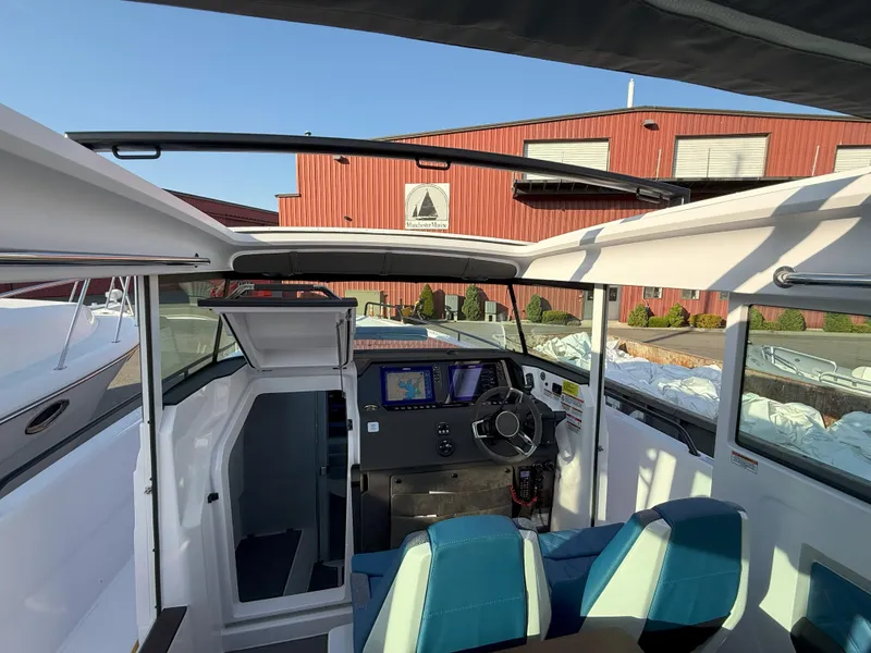 Slide: The Image of 2024 Axopar Cross Cabin interior with modern dashboard and seating, docked near a red building. - 30