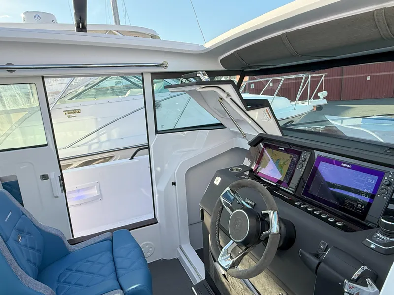 Slide: The Image of 2024 Axopar Cross Cabin interior with modern dashboard and blue seating. - 32