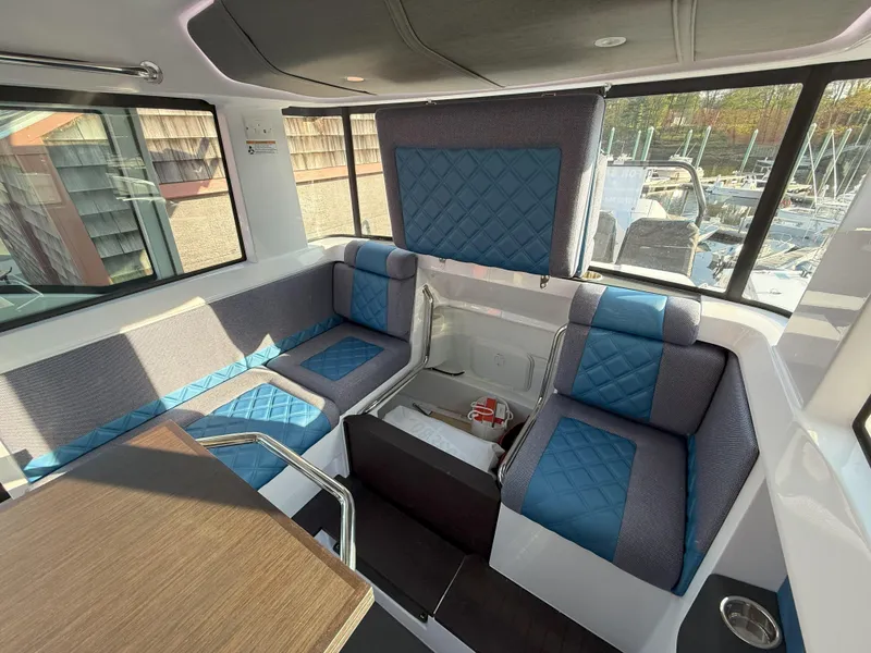 Slide: The Image of 2024 Axopar Cross Cabin interior with blue and gray seating, modern design, and ample windows. - 39