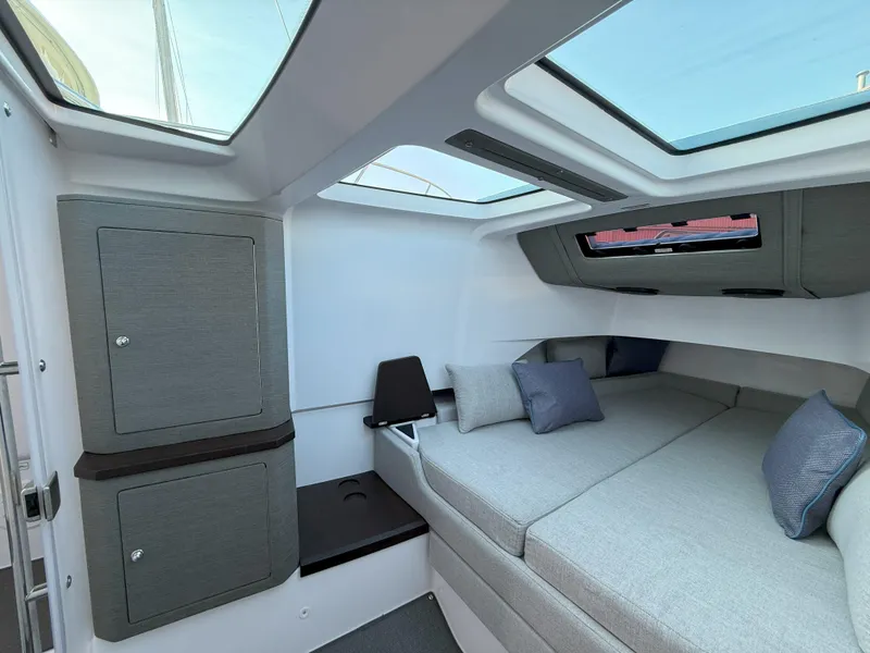Slide: The Image of 2024 Axopar Cross Cabin interior with skylights, gray seating, and storage cabinets. - 51
