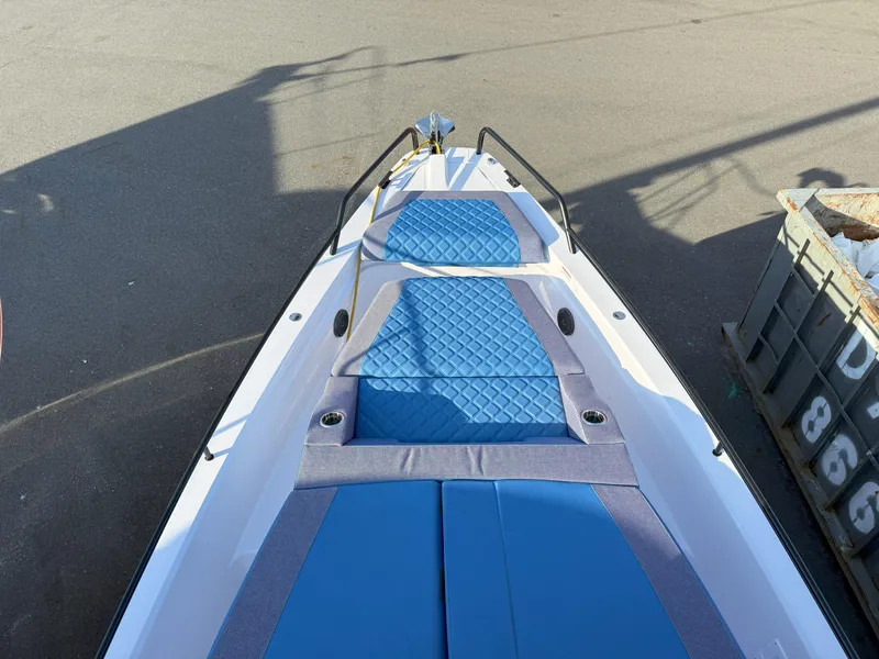 Slide: The Image of 2024 Axopar Cross Cabin boat with blue quilted seating, docked outdoors. - 7