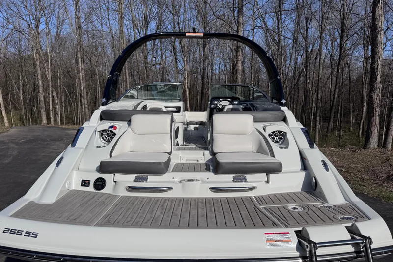 Slide: The Image of 2022 Crownline 265 SS boat with spacious seating, parked in a wooded area. - 13