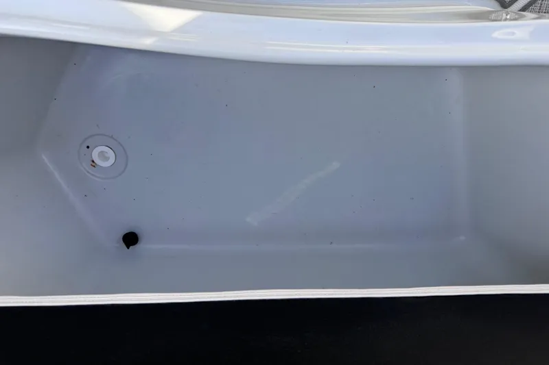 Slide: The Image of Storage compartment of a 2022 Crownline 265 SS boat, featuring a drain plug. - 23
