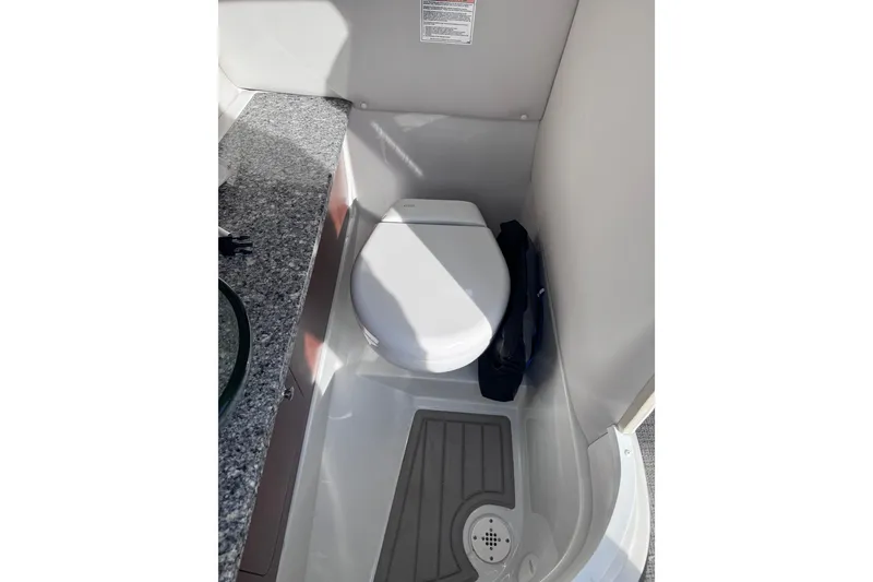 Slide: The Image of 2022 Crownline 265 SS boat interior with compact toilet and granite countertop. - 25
