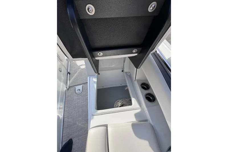 Slide: The Image of 2022 Crownline 265 SS boat interior storage compartment with open lid and cup holders. - 32