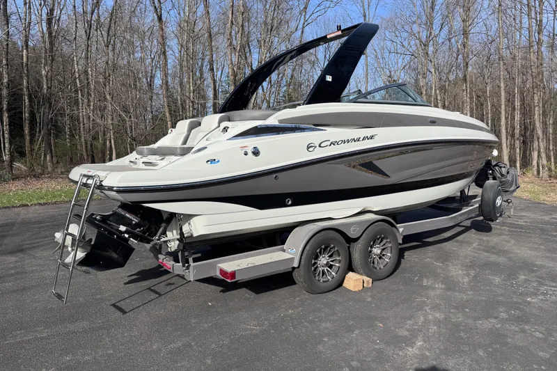 Slide: The Image of 2022 Crownline 265 SS boat on trailer, parked outdoors near trees. - 4
