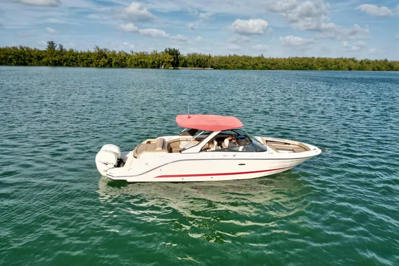 The Image of 2017 Sea Ray SLX 310 Outboard boat with red canopy on calm water. - 1