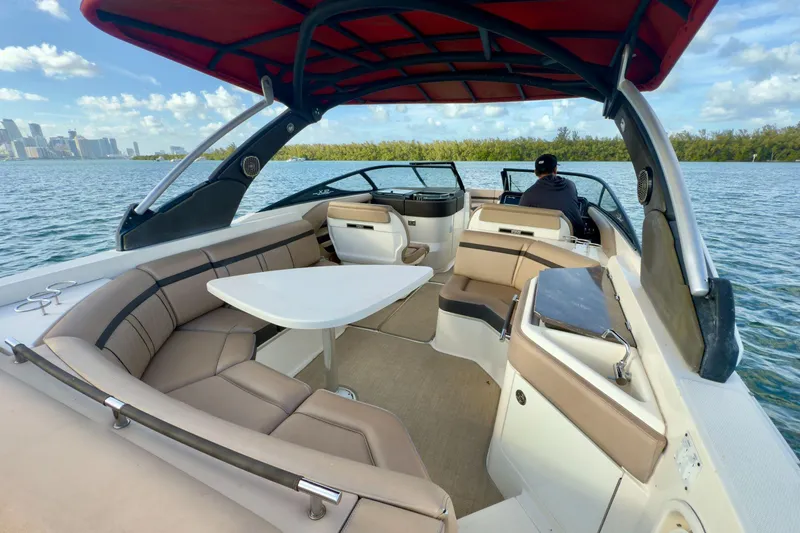 Slide: The Image of 2017 Sea Ray SLX 310 Outboard boat interior with seating and table on a sunny day. - 17