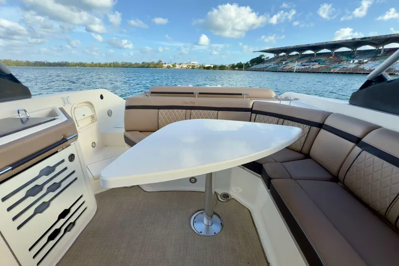 Slide: The Image of 2017 Sea Ray SLX 310 Outboard boat interior with seating and table, overlooking serene waters. - 25