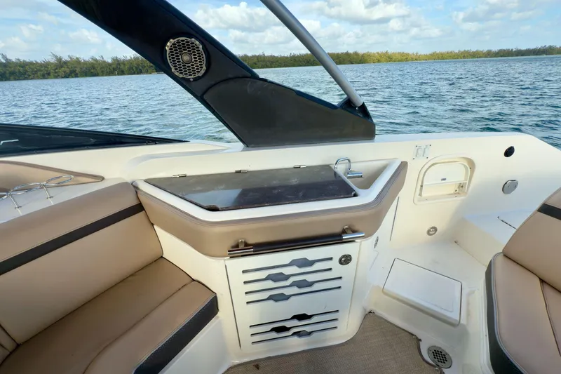 Slide: The Image of 2017 Sea Ray SLX 310 Outboard interior with seating, sink, and storage, overlooking serene waters. - 27