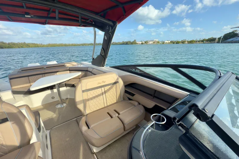 Slide: The Image of 2017 Sea Ray SLX 310 Outboard boat interior with tan seating and table on a sunny day. - 31