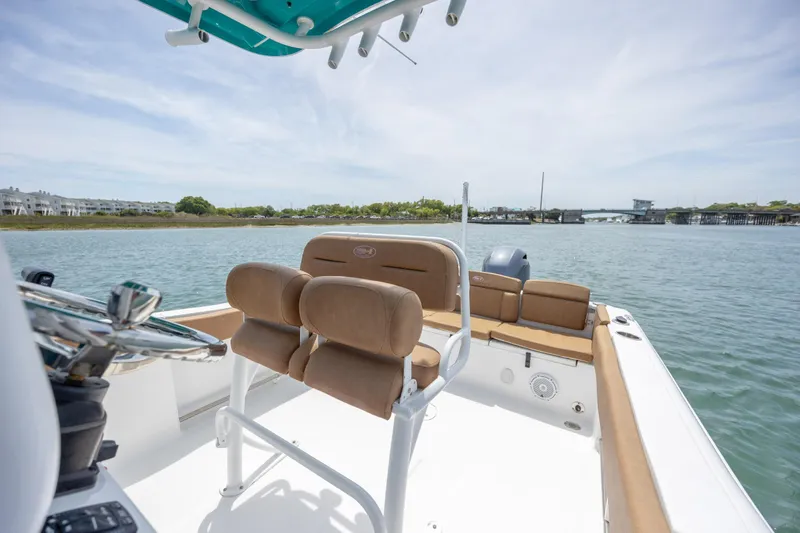 Slide: The Image of 2022 Sea Hunt Ultra 234 boat interior with tan seating on calm water. - 12