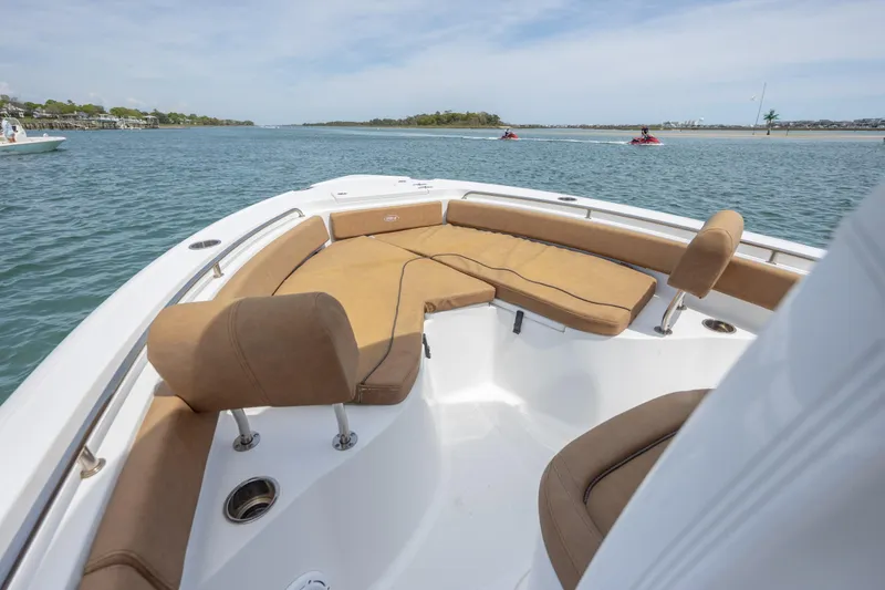 Slide: The Image of 2022 Sea Hunt Ultra 234 boat with tan seating on calm water. - 15