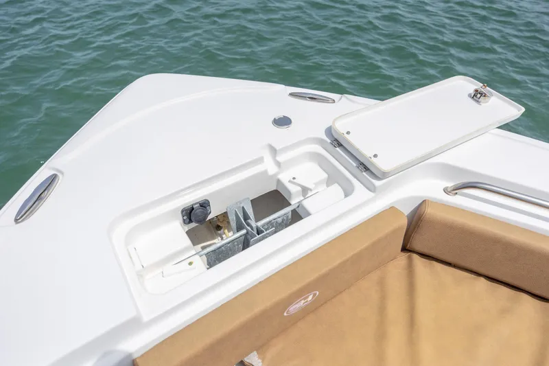 Slide: The Image of 2022 Sea Hunt Ultra 234 boat anchor compartment with open hatch, on calm water. - 16