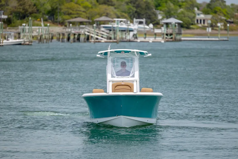 Slide: The Image of 2022 Sea Hunt Ultra 234 boat cruising on a calm lake near docks. - 2