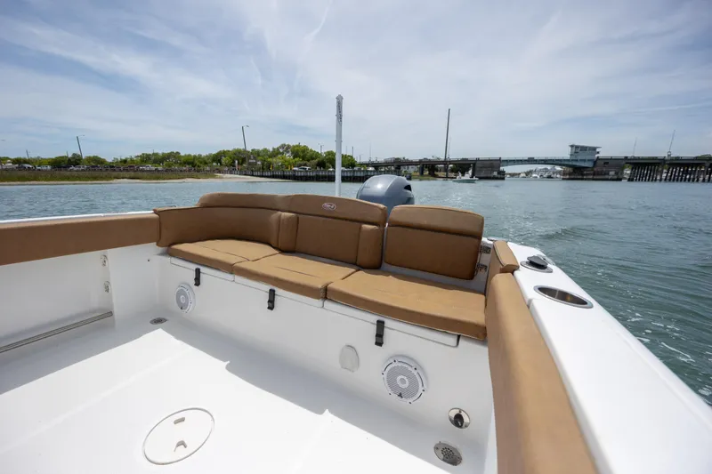 Slide: The Image of 2022 Sea Hunt Ultra 234 boat with tan seating, on calm water near a bridge. - 6