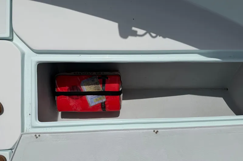 Slide: The Image of Storage compartment on 2022 Latitude Tournament Boats 25, containing a red safety kit. - 13