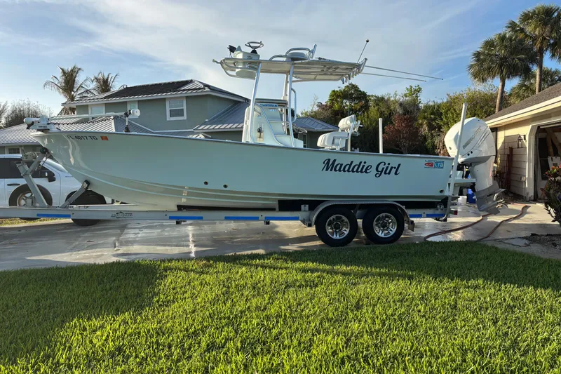 Slide: The Image of 2022 Latitude Tournament Boats 25 on trailer, labeled "Maddie Girl," in residential driveway. - 15