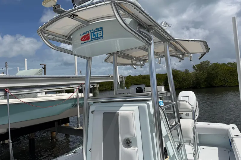 Slide: The Image of 2022 Latitude Tournament Boats 25 with T-top, docked near lush mangroves under cloudy skies. - 8