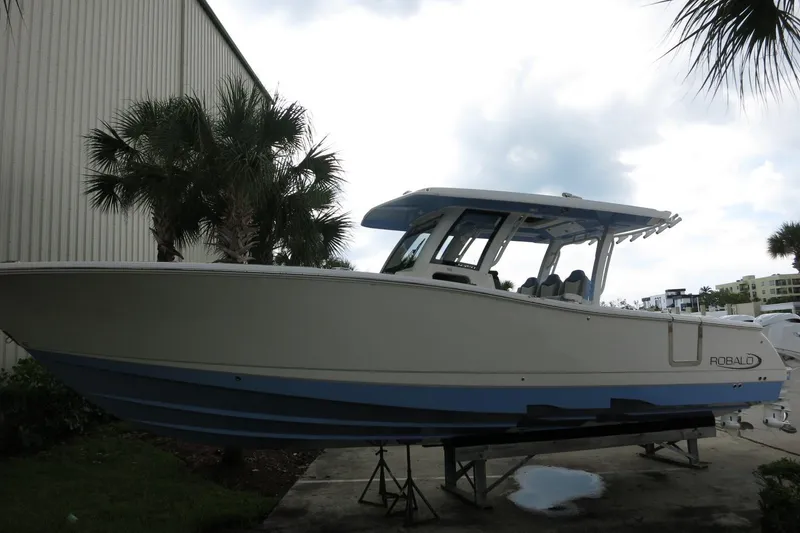 Slide: The Image of 2025 Robalo R360 Center Console boat displayed outdoors near palm trees. - 2