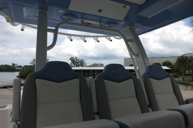Slide: The Image of 2025 Robalo R360 Center Console boat seats under blue canopy, dockside view. - 21