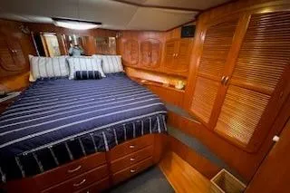 Slide: The Image of Luxurious cabin interior of 1993 Mikelson 50 Sportfisher with wood finish and striped bedding. - 5