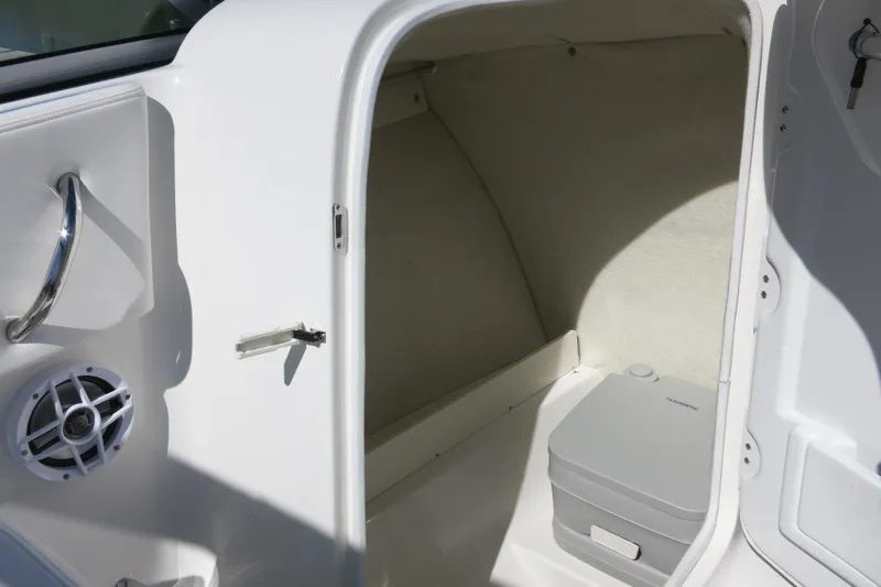 Slide: The Image of 2026 Robalo R207 Dual Console boat interior with storage compartment and portable toilet. - 17