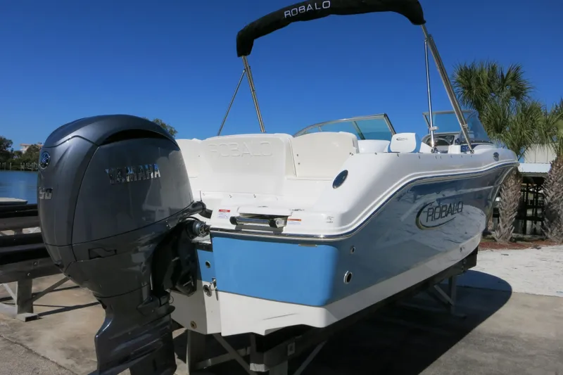 Slide: The Image of 2026 Robalo R207 Dual Console boat with Yamaha engine, docked near palm trees. - 2