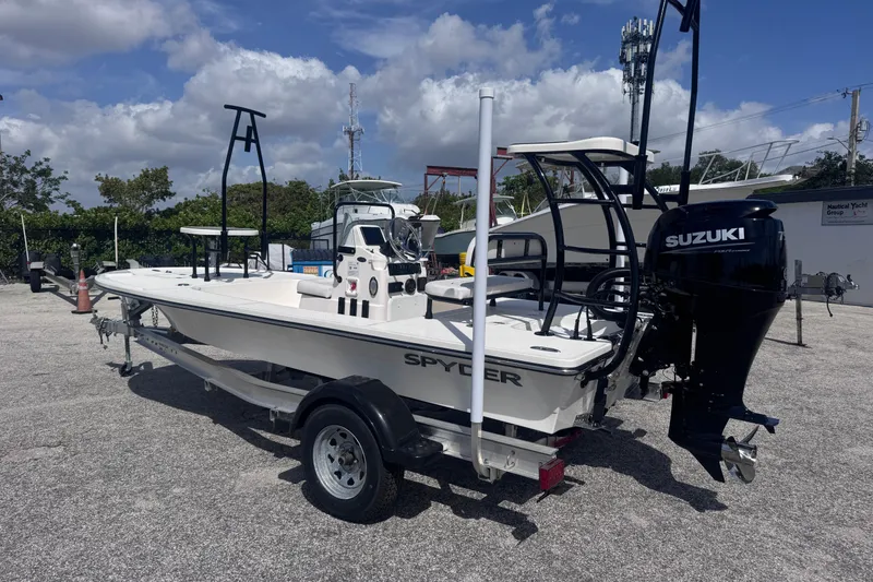 Slide: The Image of 2026 Spyder FX17 Flicker boat with Suzuki engine on trailer, parked outdoors. - 2