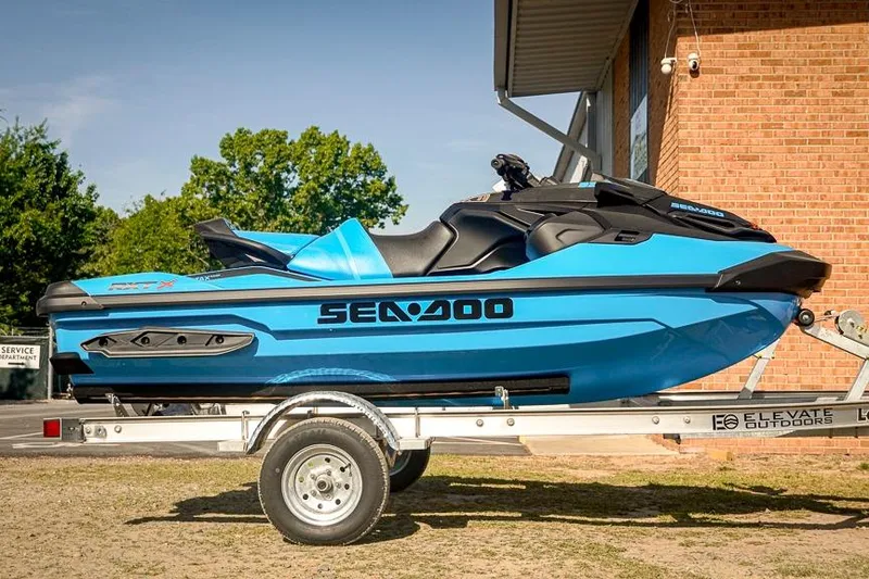 The Image of 2026 Sea-Doo RXT-X 325 jet ski on trailer, vibrant blue color, parked outdoors. - 0