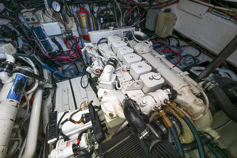 Slide: The Image of Engine room of a 2000 Pursuit 3400 Express boat, showcasing complex machinery and wiring. - 54