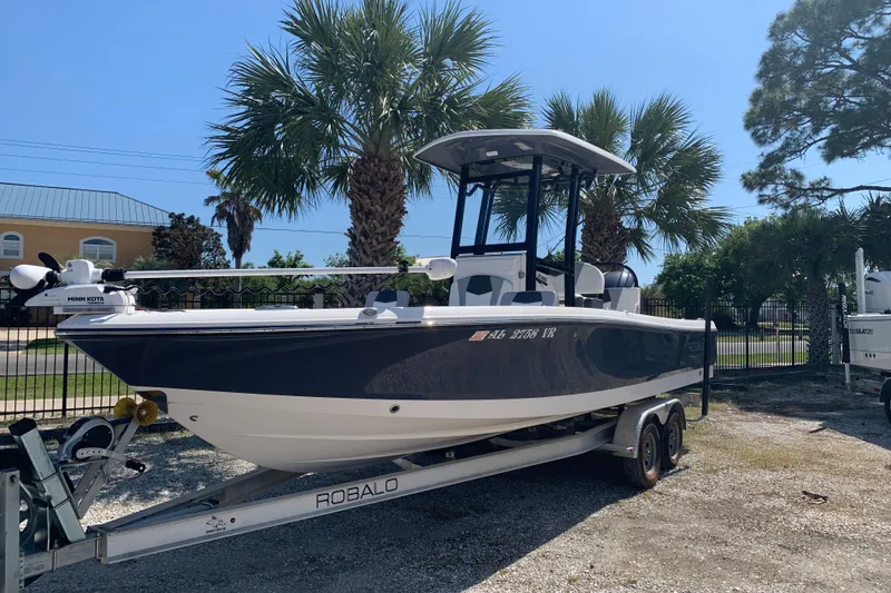 Slide: The Image of 2022 Robalo 246 Cayman boat on trailer, parked near palm trees. - 3