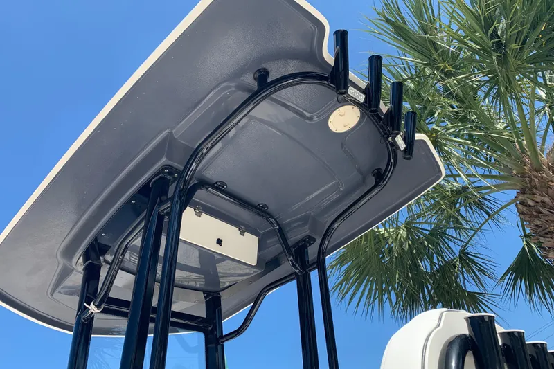 Slide: The Image of T-top of 2022 Robalo 246 Cayman boat against blue sky and palm trees. - 4