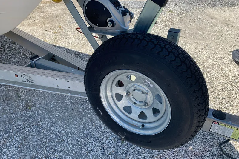 Slide: The Image of Trailer wheel of a 2022 Robalo 246 Cayman boat on gravel surface. - 8