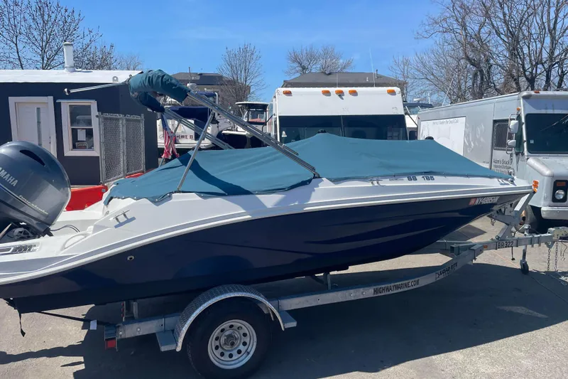 Slide: The Image of 2023 Hurricane SunDeck Sport 185 OB boat on trailer, covered, parked outdoors. - 2