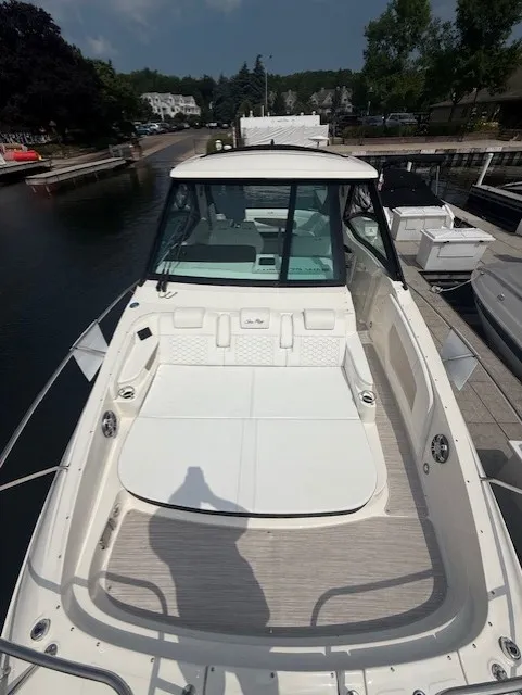 Slide: The Image of The image shows a 2026 Sea Ray Sundancer 320 docked. It features a spacious foredeck with cushioned seating and a glass canopy. - 17