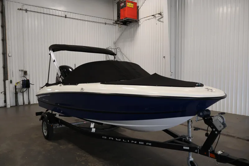 Slide: The Image of 2019 Bayliner 160 Bowrider boat with cover on trailer in indoor storage. - 33