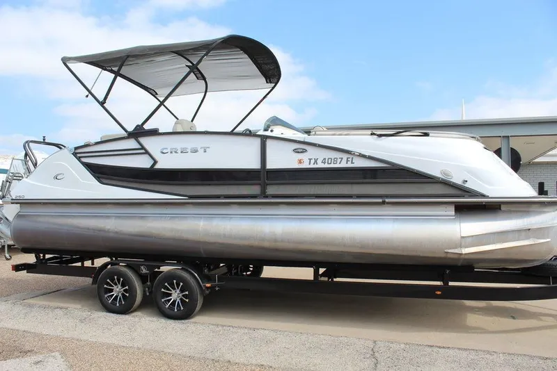 Slide: The Image of 2019 Crest Savannah 250 SLRC pontoon boat on trailer, featuring sleek design and canopy. - 3