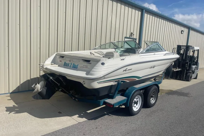 Slide: The Image of 1996 Sea Ray 210 Bow Rider boat on trailer near warehouse. - 2