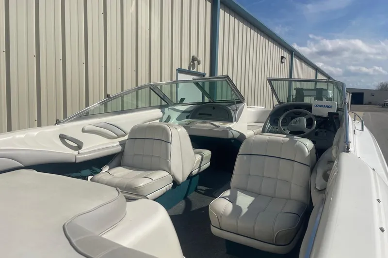 Slide: The Image of 1996 Sea Ray 210 Bow Rider interior with white seating and steering wheel, parked outdoors. - 5