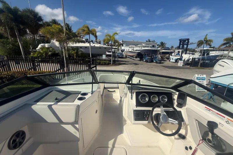 Slide: The Image of 2020 Sea Ray SPX 210 Outboard boat interior with steering wheel and dashboard, docked under blue sky. - 10