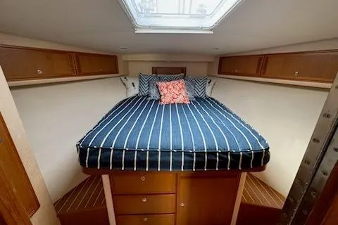 Slide: The Image of 2008 Cabo 40 Express cabin interior with striped bedding and wooden storage. - 8