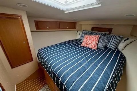 Slide: The Image of 2008 Cabo 40 Express cabin with striped bedding and decorative pillows. - 9