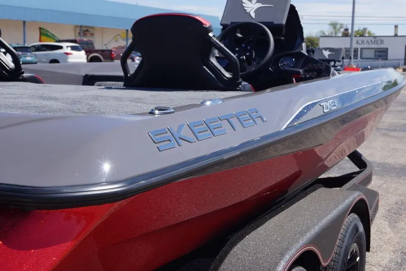 Slide: The Image of 2026 Skeeter ZXE21 boat, sleek design, red and gray finish, parked outdoors. - 8