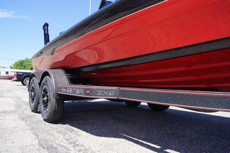 Slide: The Image of 2026 Skeeter ZXE21 boat on trailer, showcasing sleek red design and dual axles. - 9