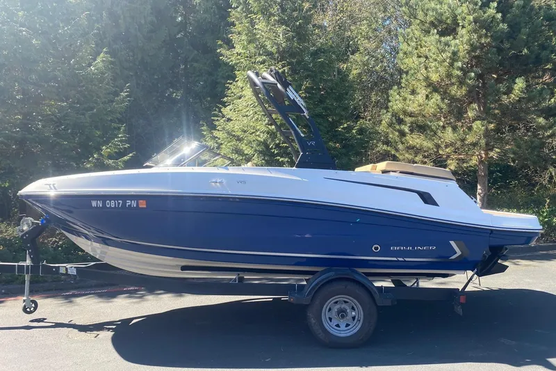 The Image of 2023 Bayliner VR5 Bowrider I/O boat on trailer, surrounded by trees. - 0