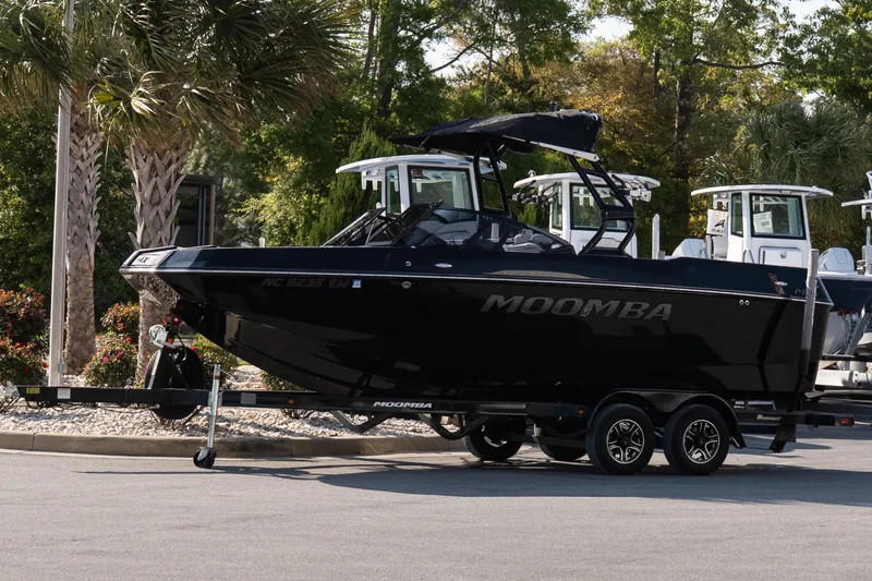The Image of 2022 Moomba Max boat on trailer, parked outdoors with trees in the background. - 1