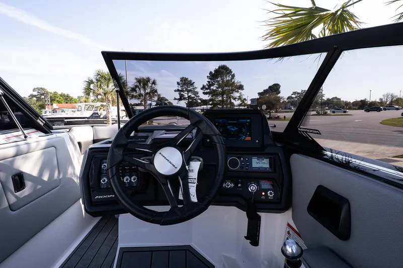 Slide: The Image of 2022 Moomba Max boat dashboard with steering wheel and control panel, parked outdoors. - 11